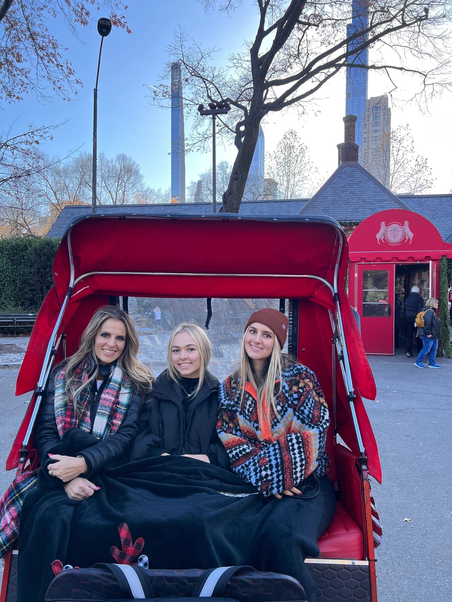 Three guests seated in a red pedicab at a Central Park entrance during a Gossip Girl tour