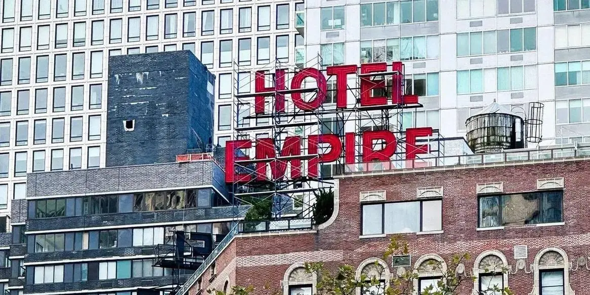 Close view of the HOTEL EMPIRE rooftop sign against Upper West Side buildings — Gossip Girl Tours photo stop in New York