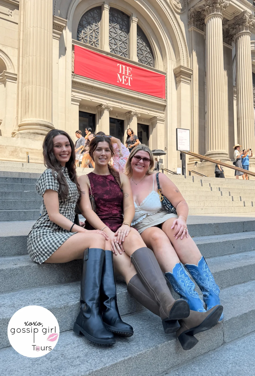Three Gossip Girl Tours guests seated on the Metropolitan Museum of Art steps beneath The Met banner